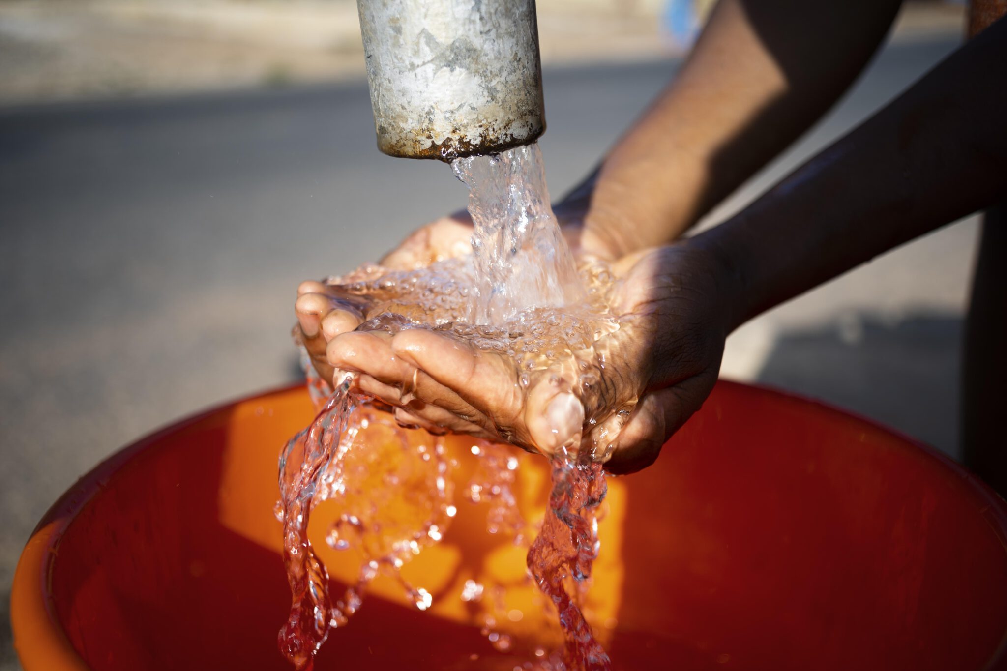 african-woman-pouring-water-recipient-outdoors