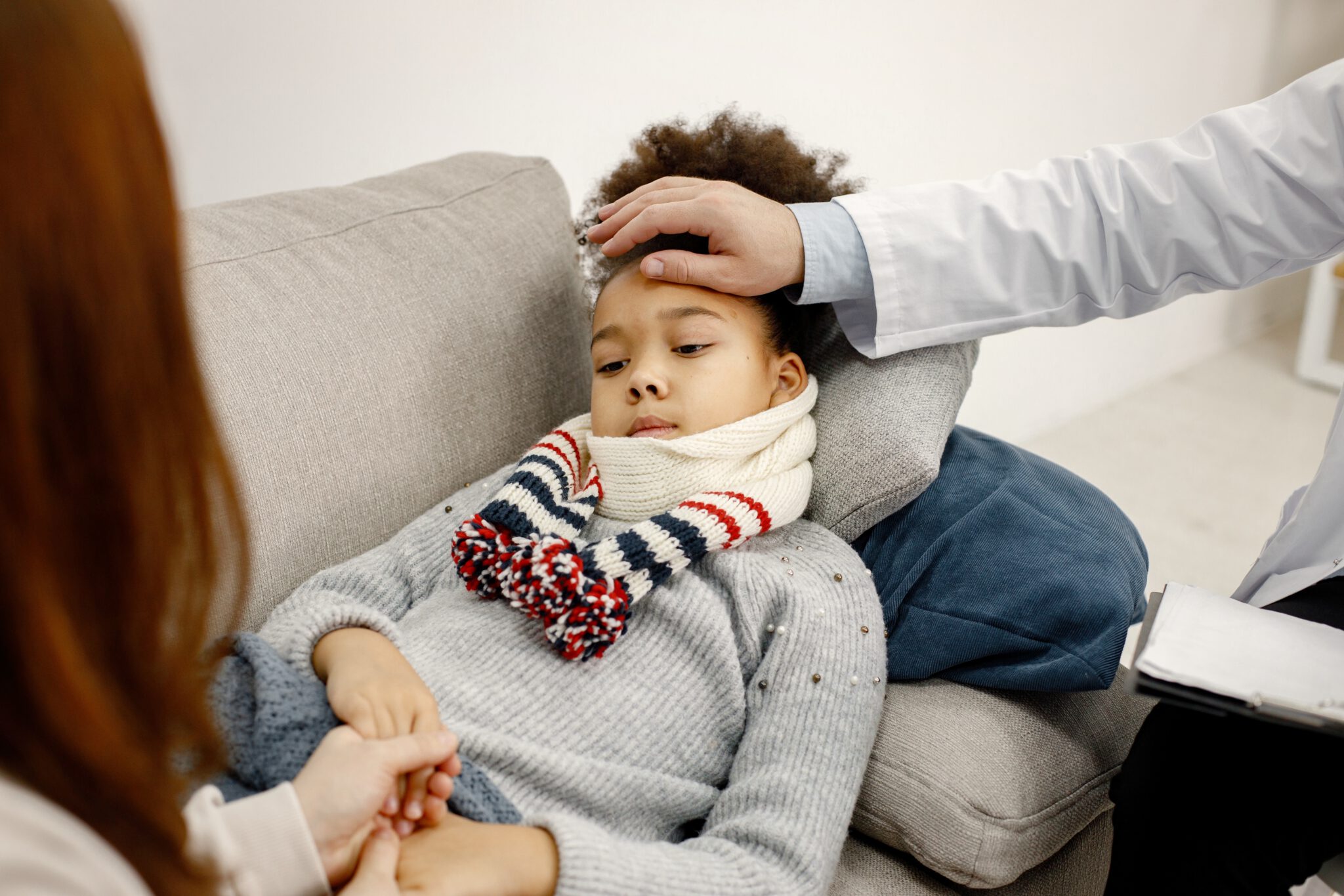 Male pediatrician holding hand on a forehead of sick little blac